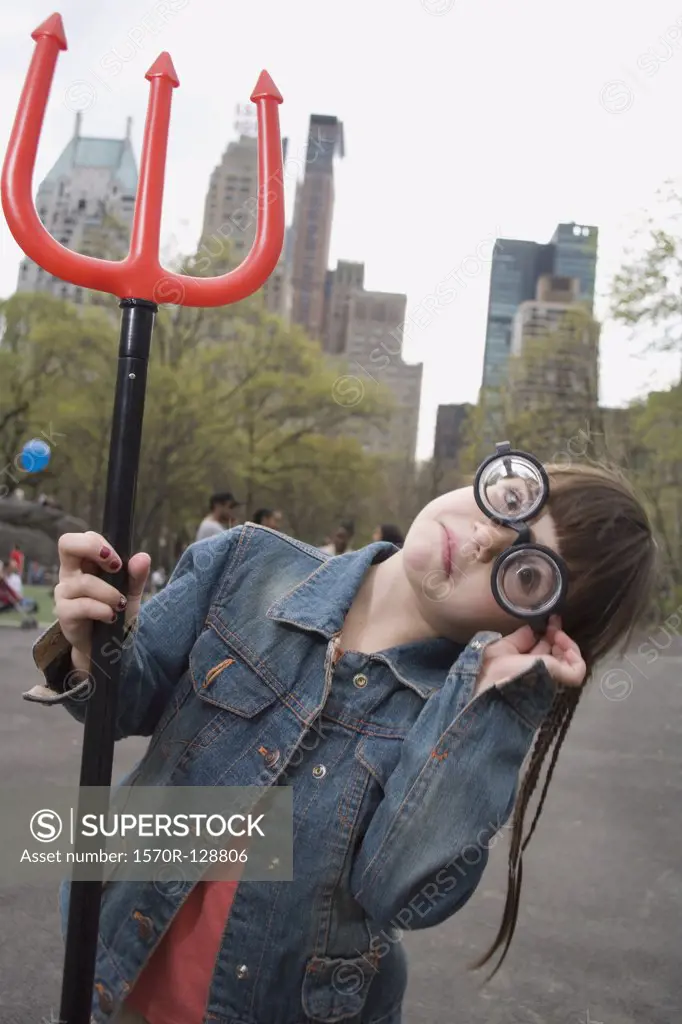 A young girl wearing funny glasses and holding a devil's pitchfork