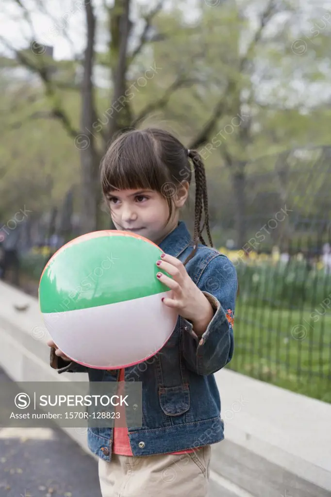 A young girl holding an inflatable ball in Central Park, New York City