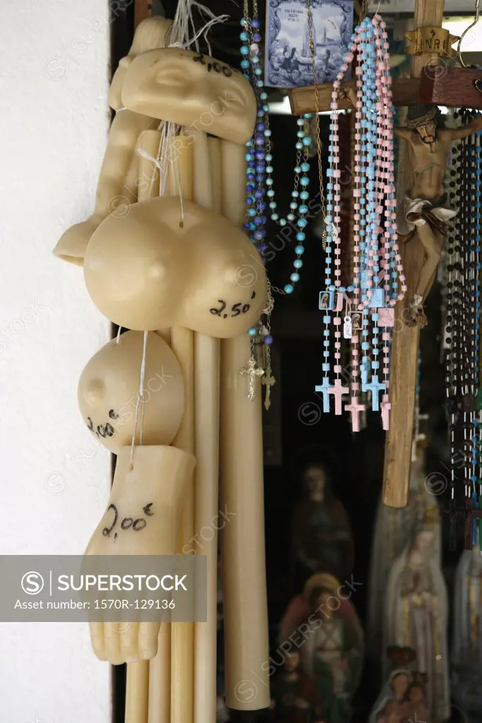 Wax body parts and rosary beads hanging in a store