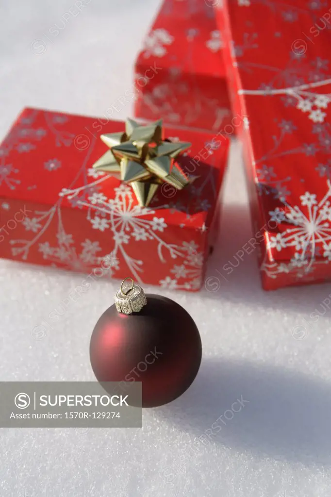 A Christmas ornament and Christmas presents on the snow