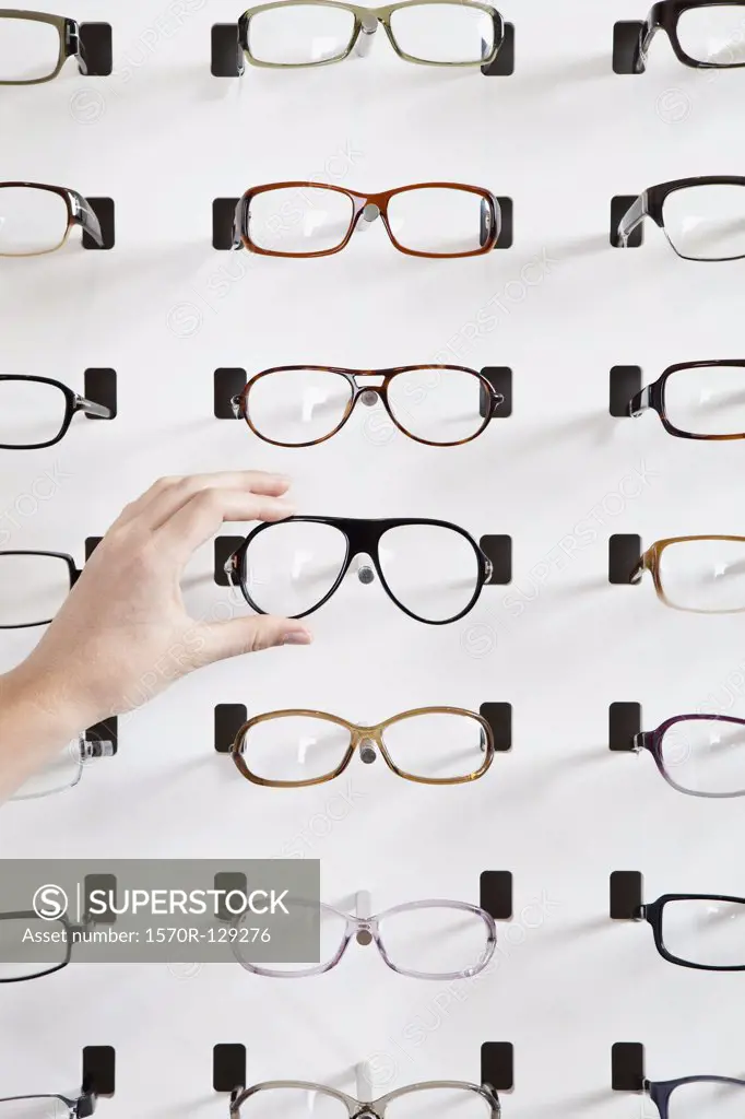 A human hand choosing a pair of glasses in an eyewear store