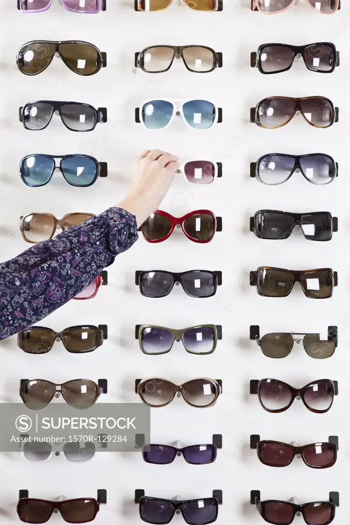 A human hand choosing a pair of sunglasses in an eyewear store