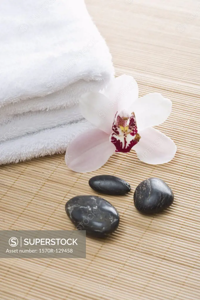 Folded towels, Lastone therapy stones and an orchid arranged on a tatami mat