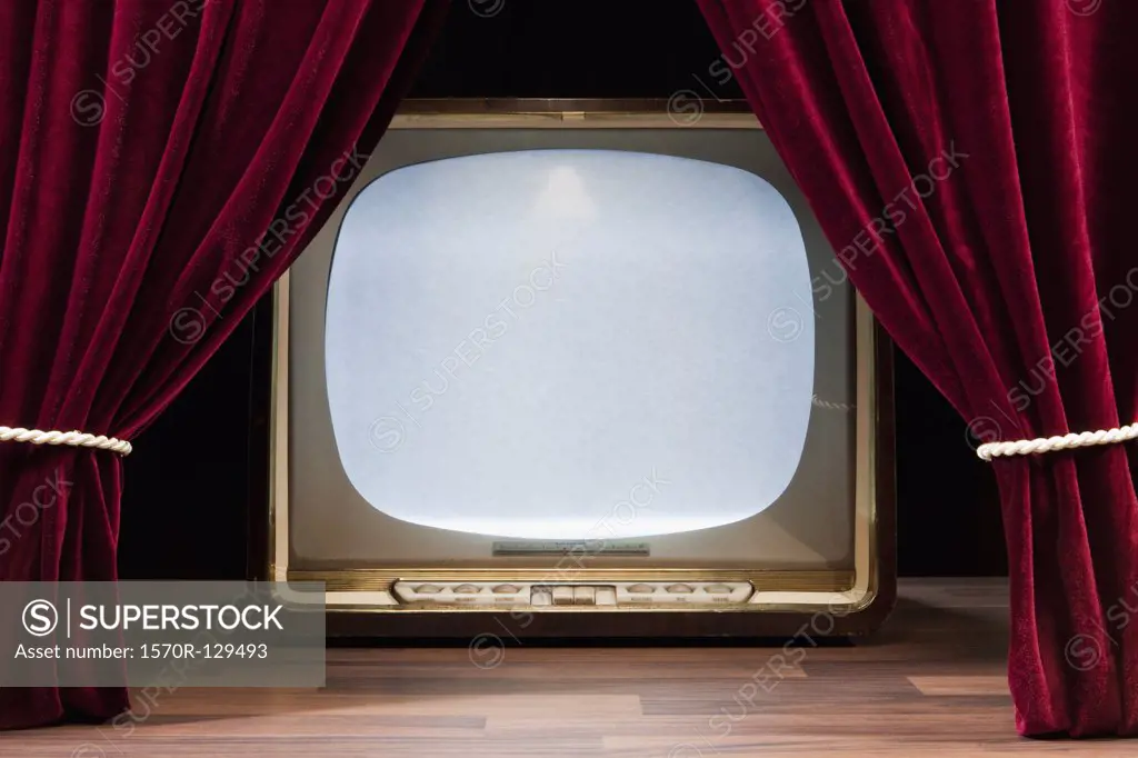 An Old Fashioned Television Behind Red Theatre Curtains