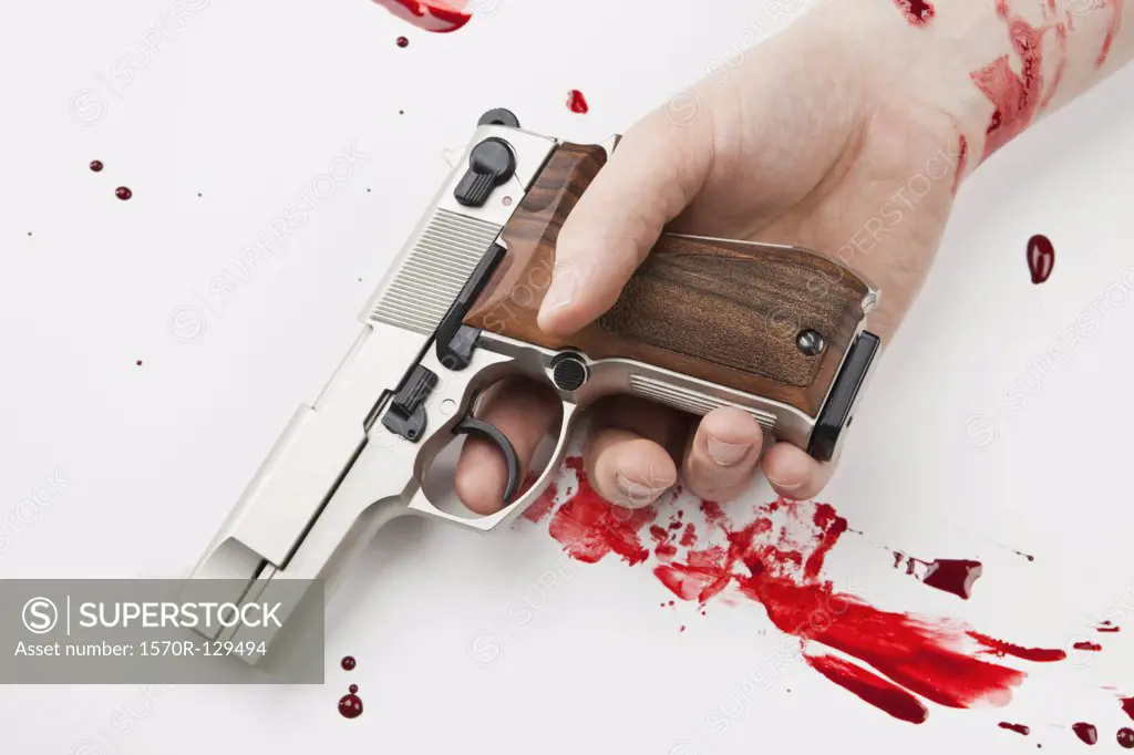 A Hand Holding A Gun Splattered With Blood