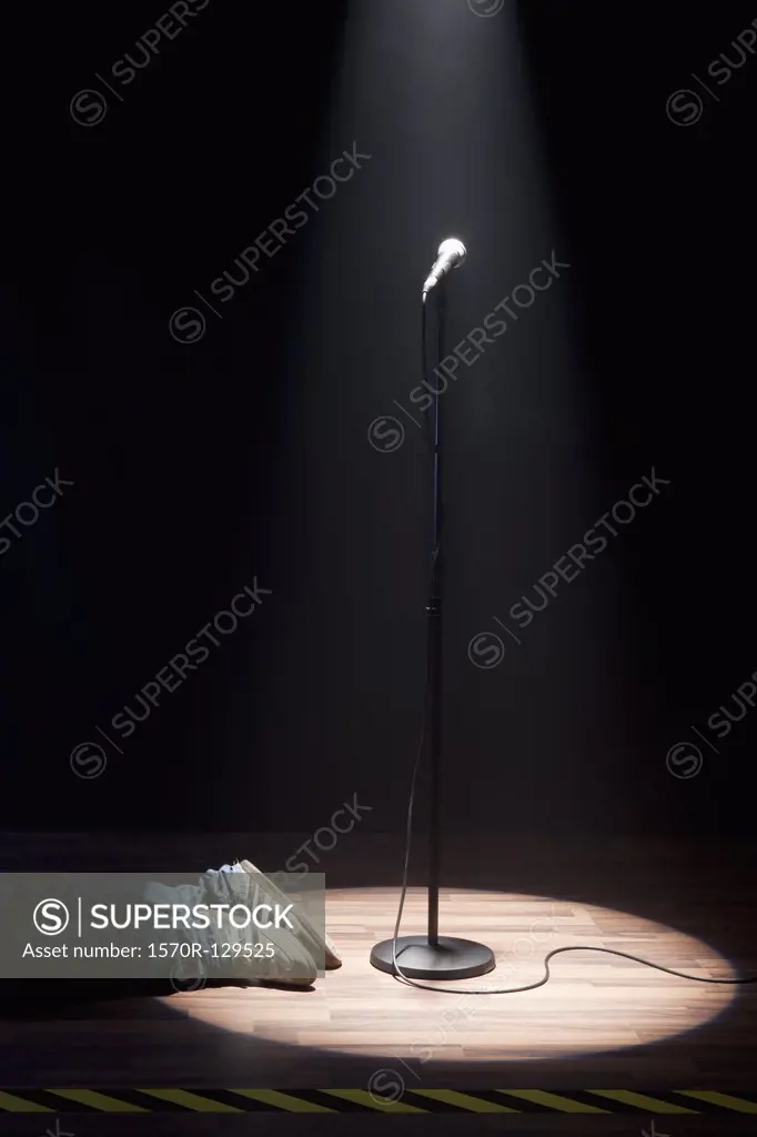 A Person Lying On A Stage Next To A Spot Lit Microphone