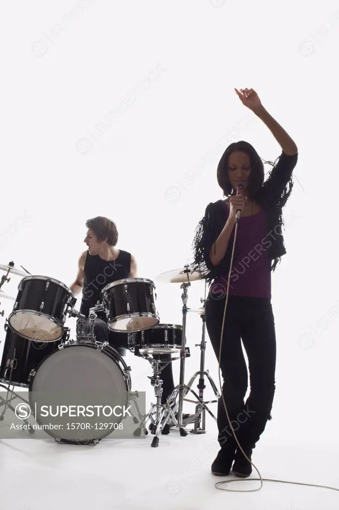 A female singer and a drummer performing, studio shot, white background, back lit
