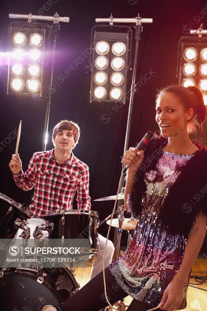 A woman singer accompanied by a man on drums performing on stage