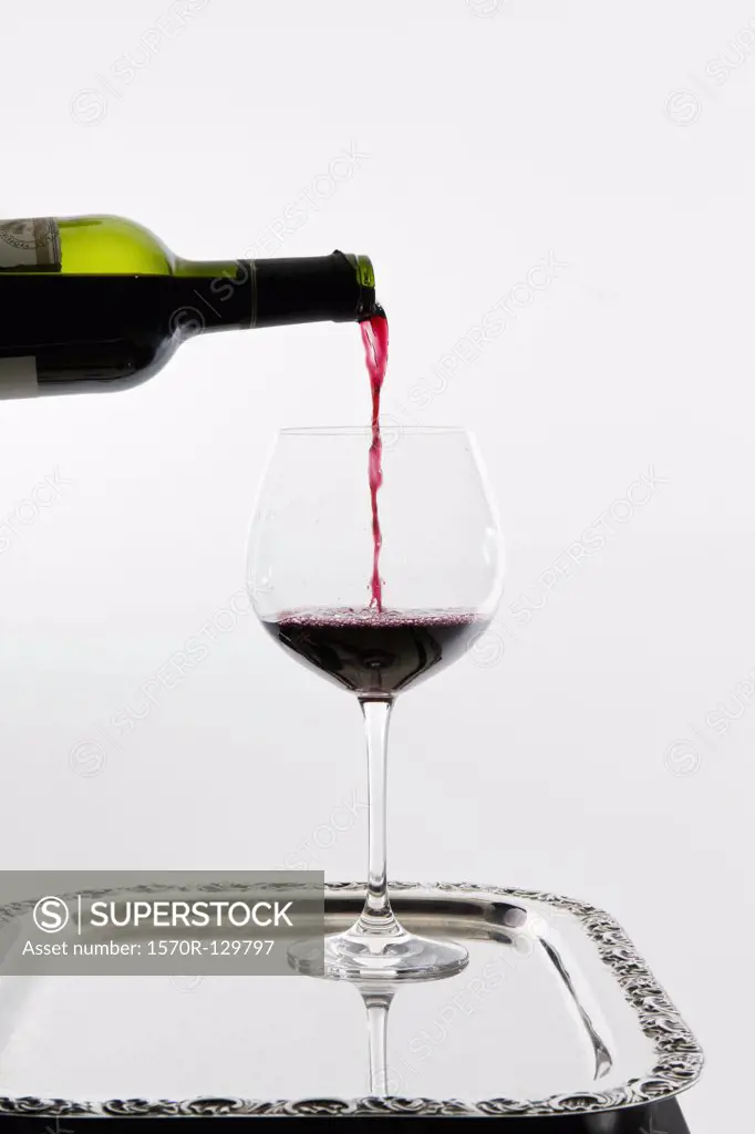 Red wine being poured into a wineglass on a tray