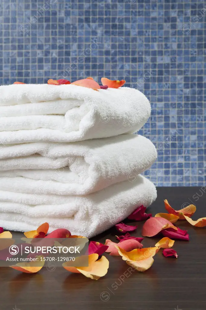 A stack of folded towels with rose petals