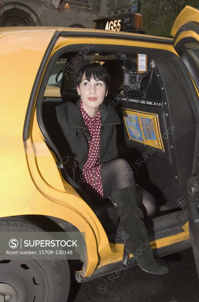 Young woman stepping out of a yellow taxi, New York City