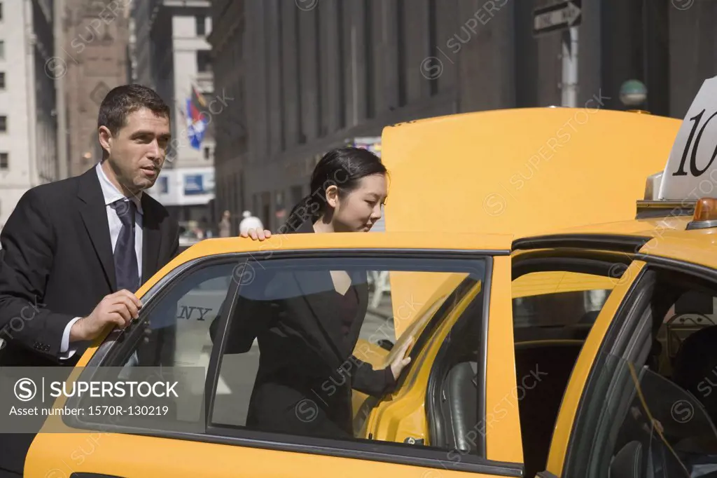 Businessman and businesswoman entering yellow taxi