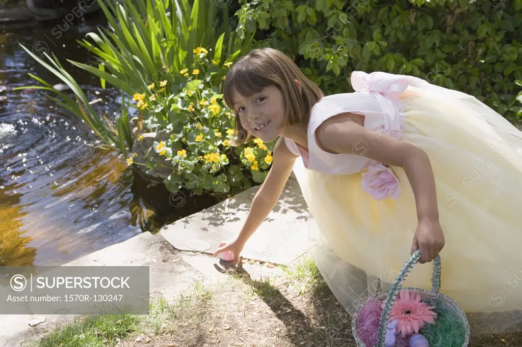 Young girl crouching down to reach Easter egg