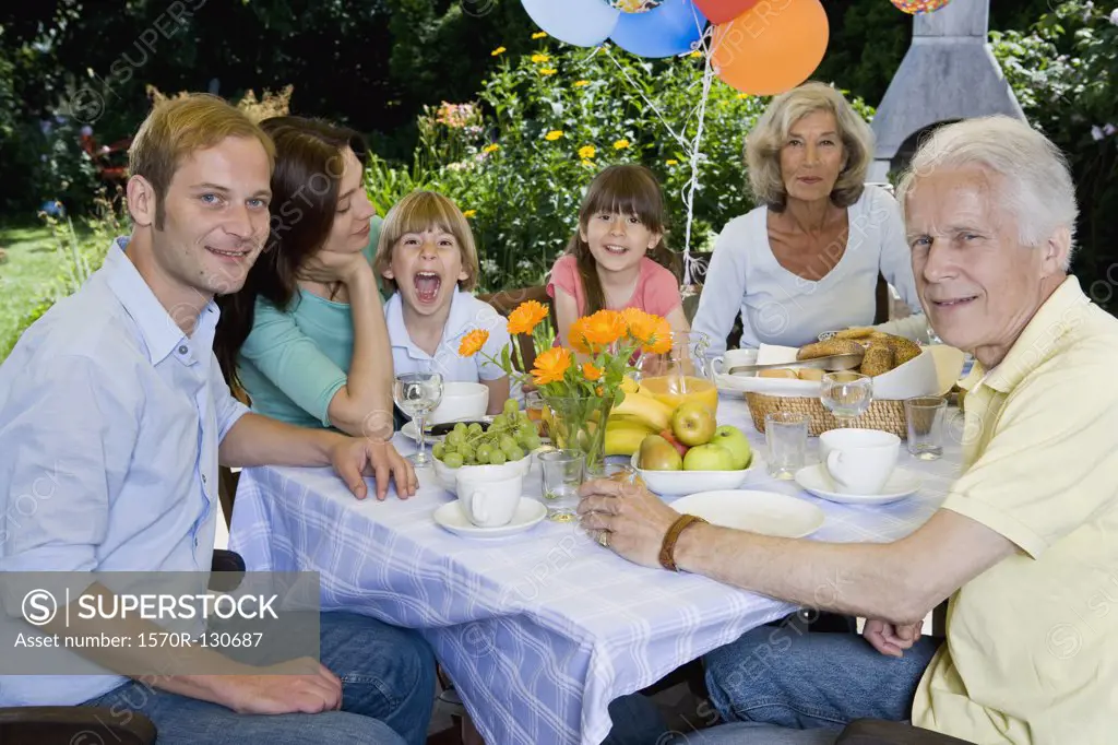 A multi-generational family having breakfast, outdoors