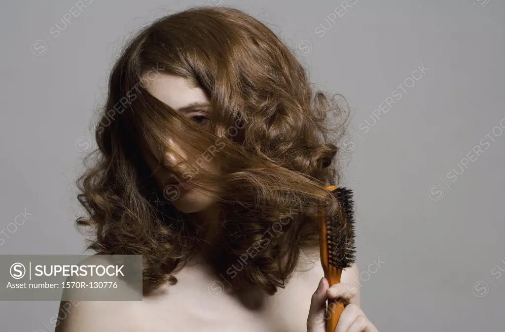 A young woman pulling hair over her face with a brush