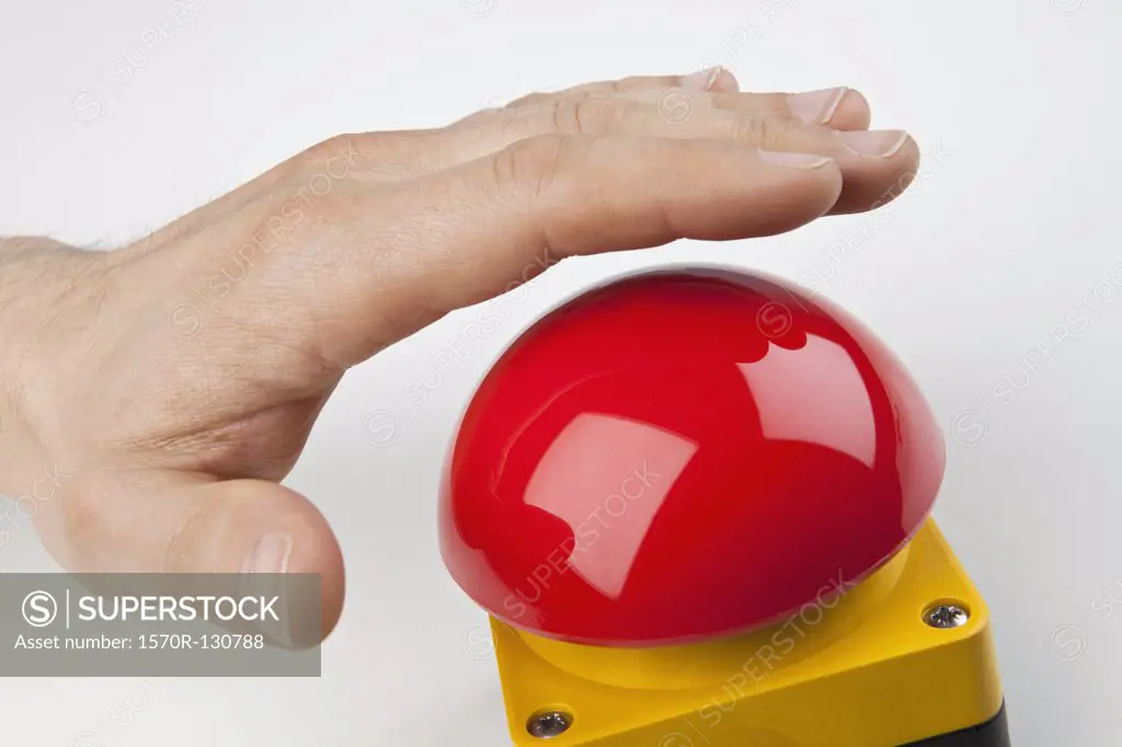 A hand about to press a big red buzzer