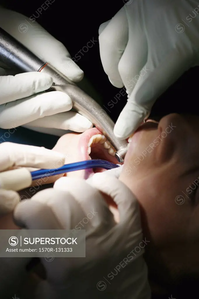 Close-up of a dentist and a dental assistant working on a female patient