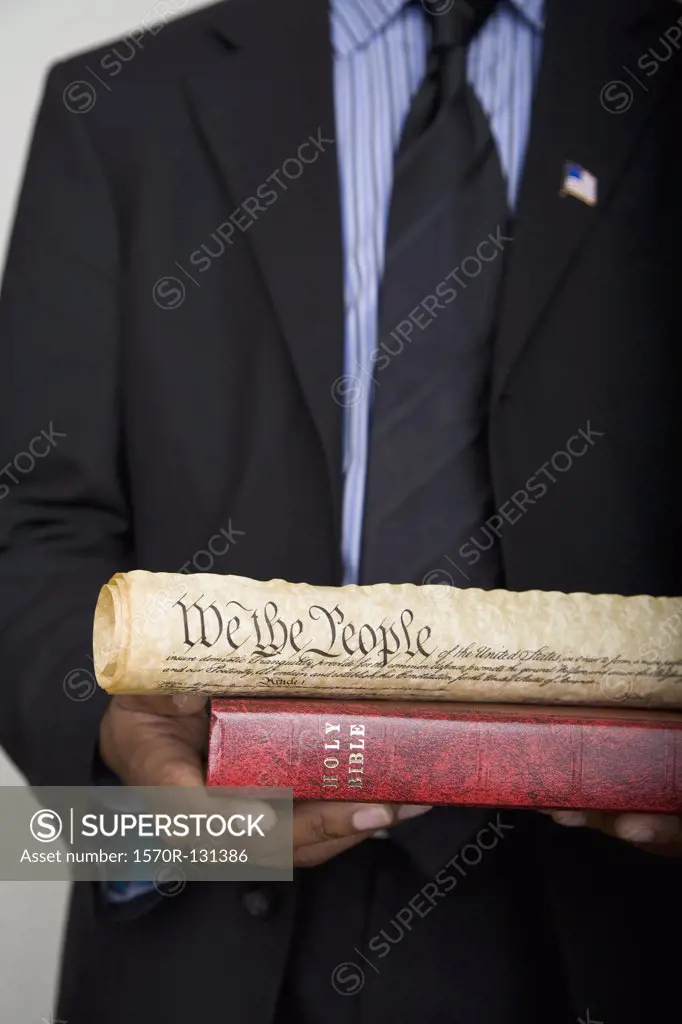 Detail of a man holding a Bible and a scroll of the American Constitution