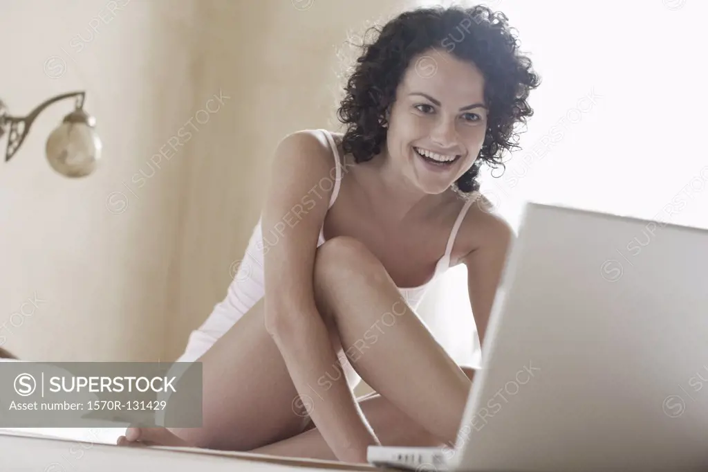 A woman sitting on her bed and using her laptop