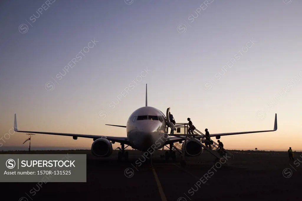 People boarding an airplane at dusk