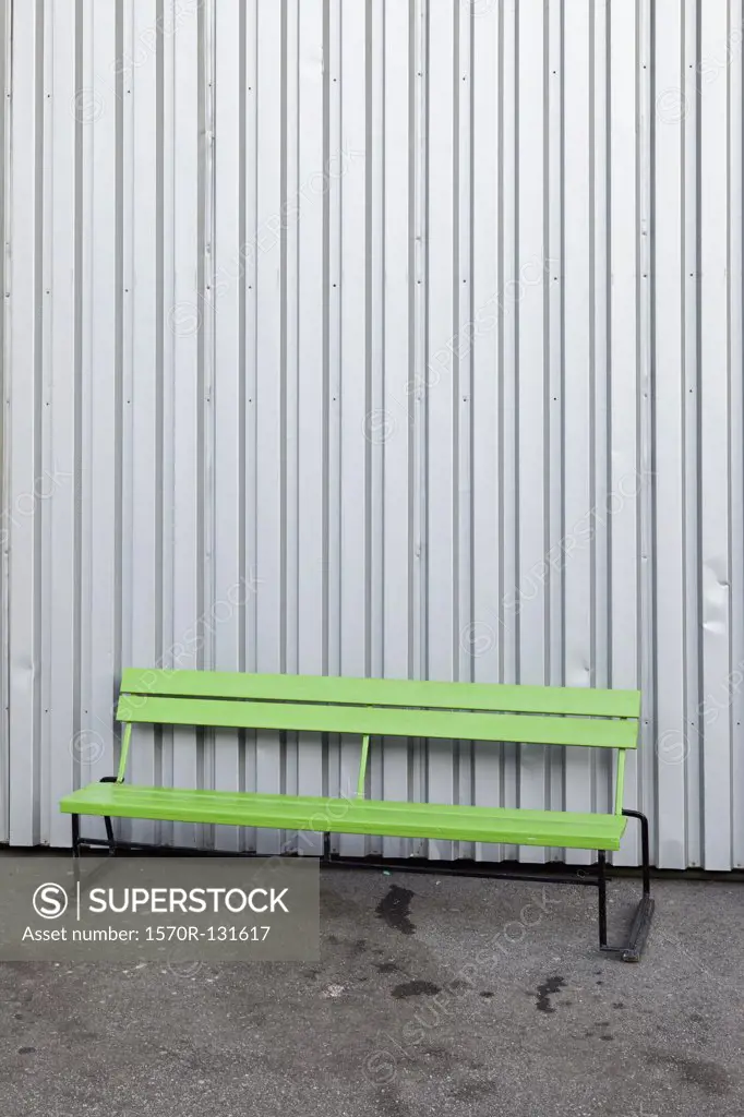 A green bench in front of a steel building
