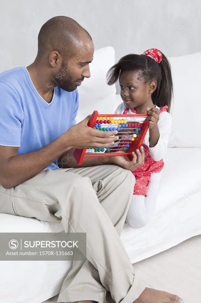 A father showing his young daughter how to use an abacus