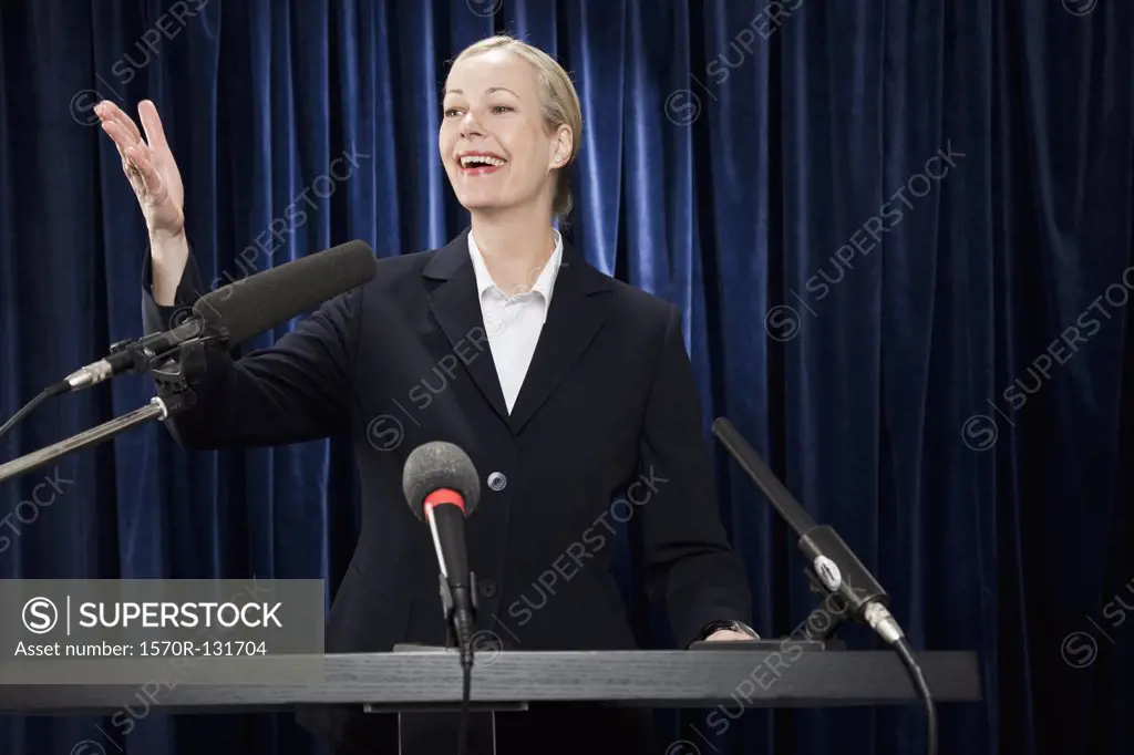 A woman in a suit gesturing at a lectern