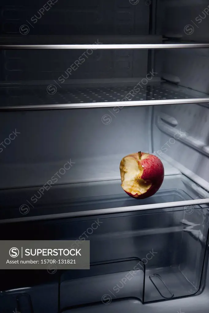 A half eaten apple in an empty refrigerator