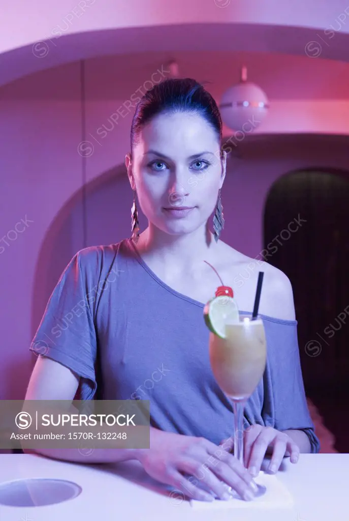 Young woman standing at a bar with a cocktail