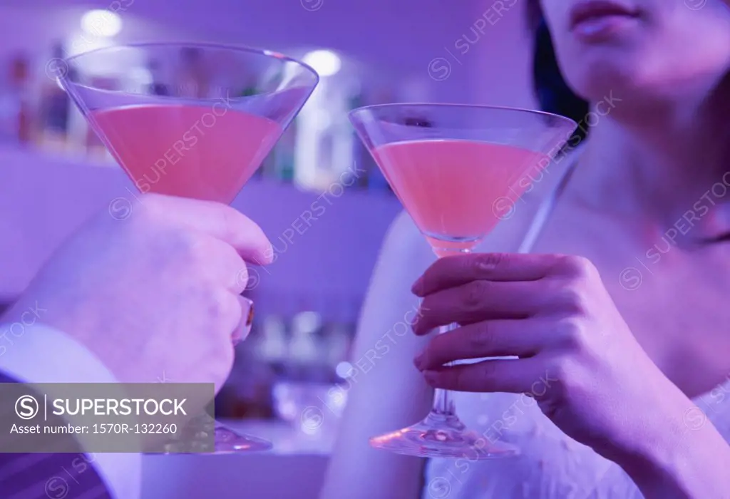 Young man and young woman toasting with cocktails