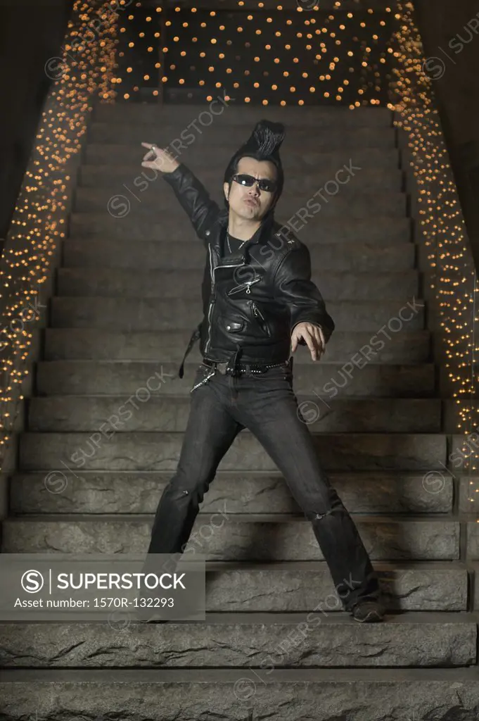 Man posing on steps dressed in rock and roll outfit, Tokyo, Japan