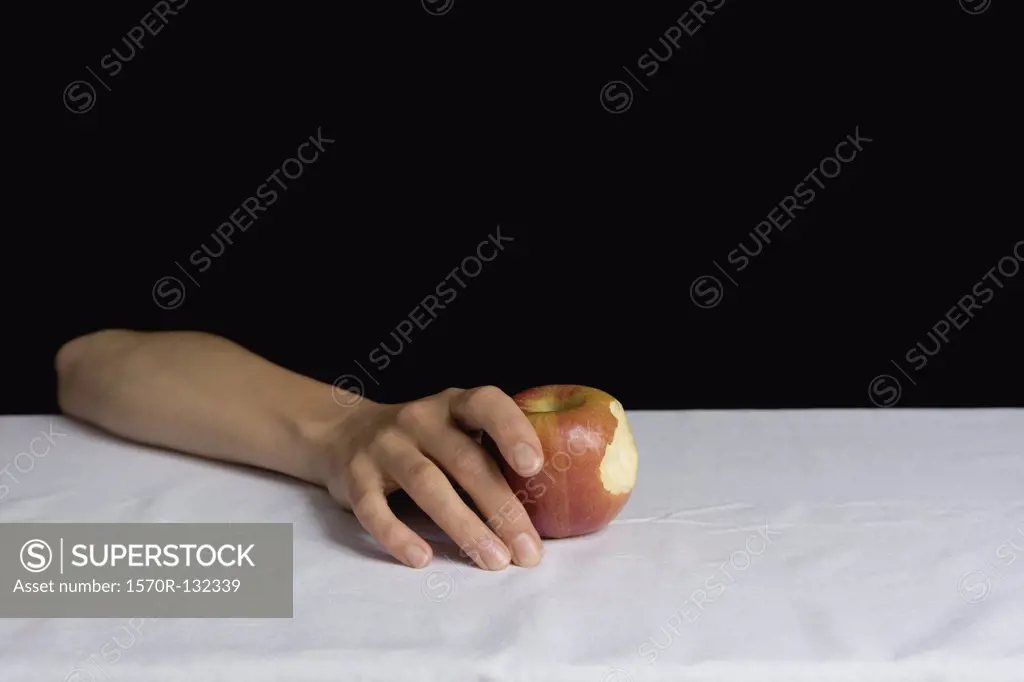 Arm resting on table and holding apple