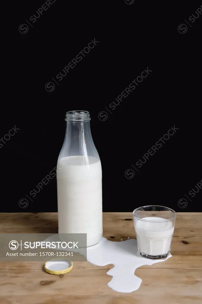 Milk bottle and glass in puddle of spilt milk