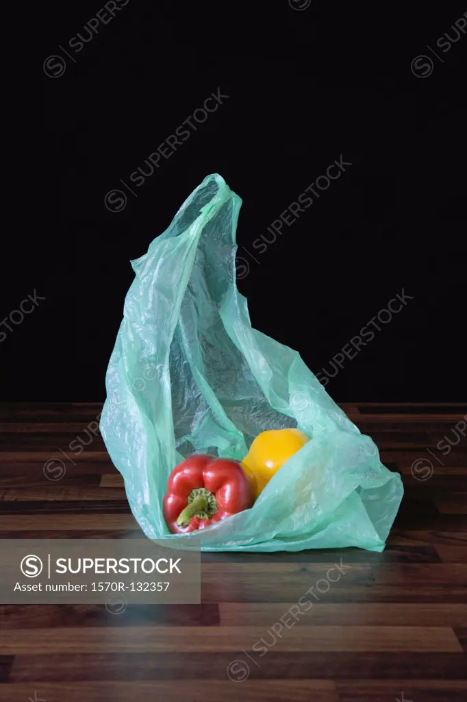 Bell peppers in plastic shopping bag in wooden table