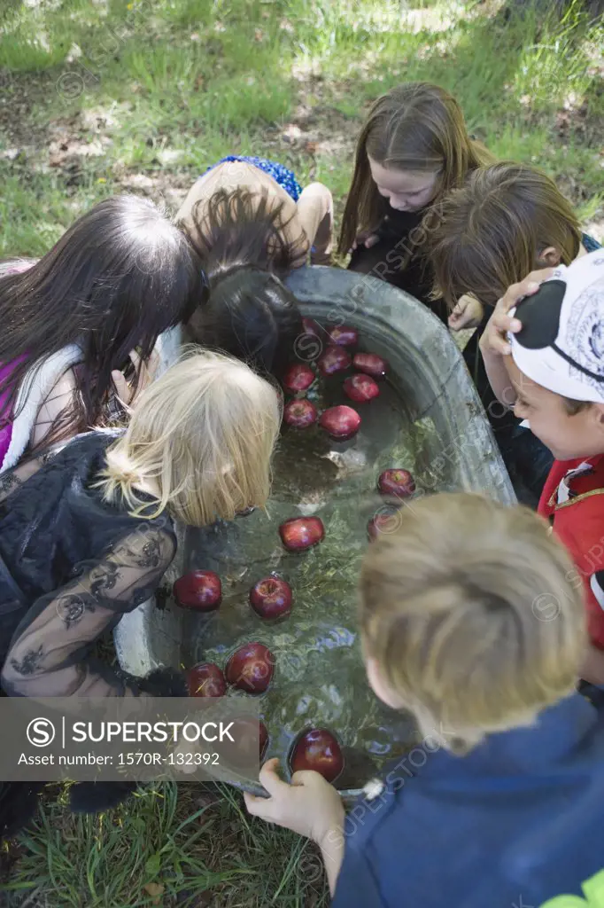 Group of children bobbing for apples at Halloween party