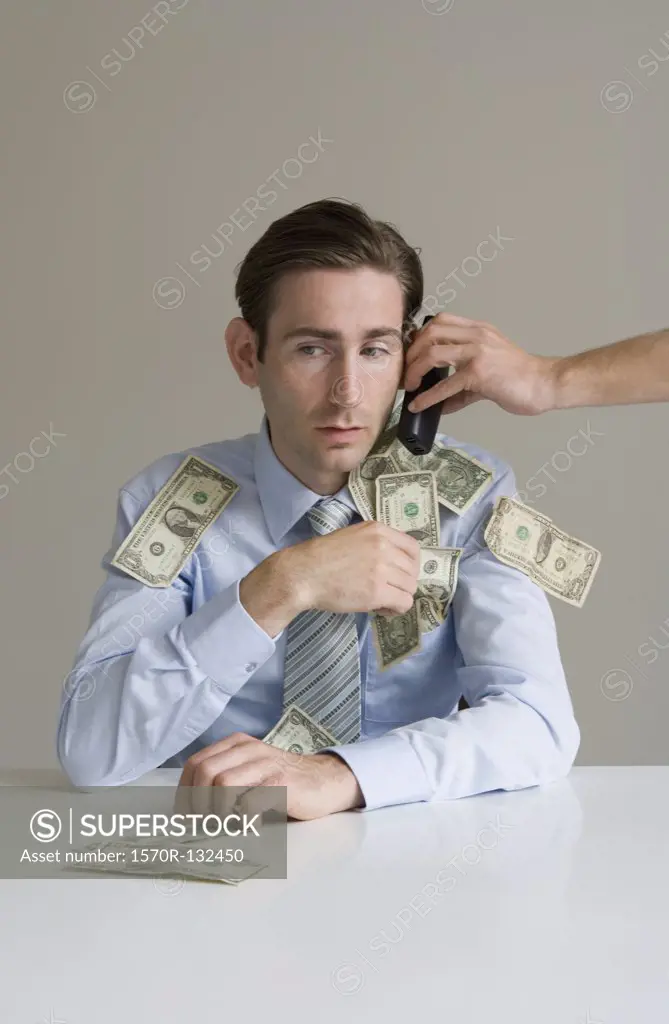 Businessman using telephone covered in money