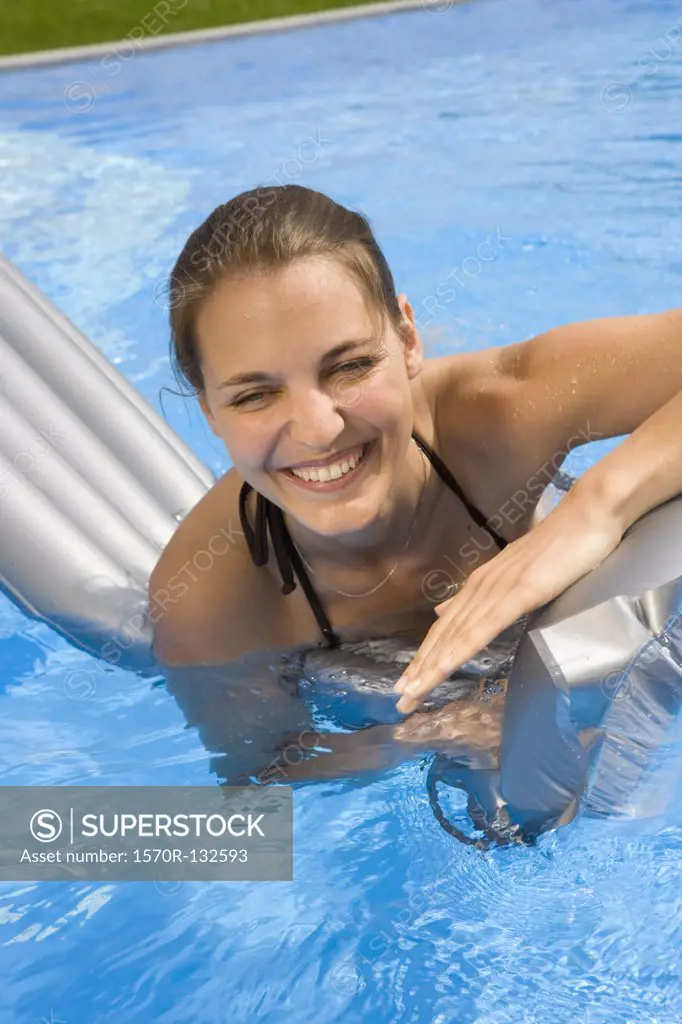 A young woman playing on an inflatable raft in a swimming pool