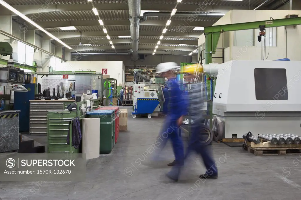 Two manual workers walking through a factory, blurred motion, long exposure