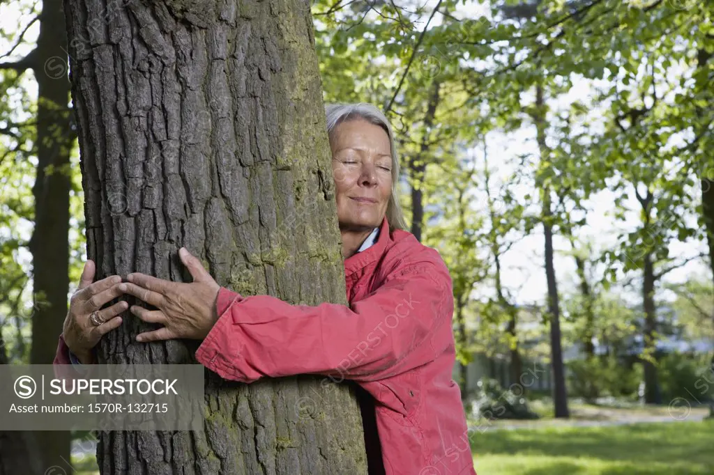A senior woman hugging a tree