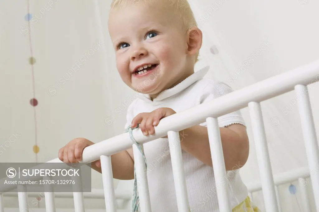 A toddler standing in a baby crib