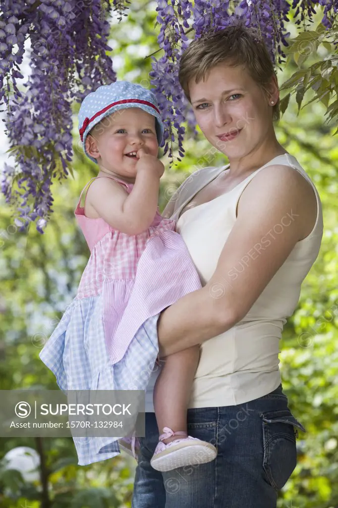 A formal portrait of a mother and her baby girl standing under a wistera