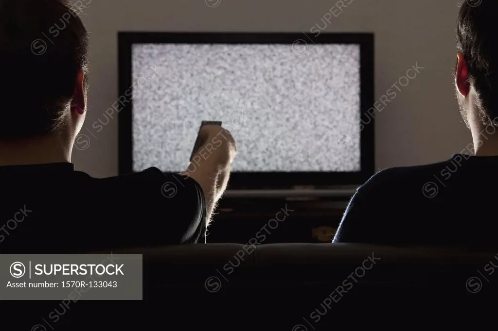 Two men watching static on television