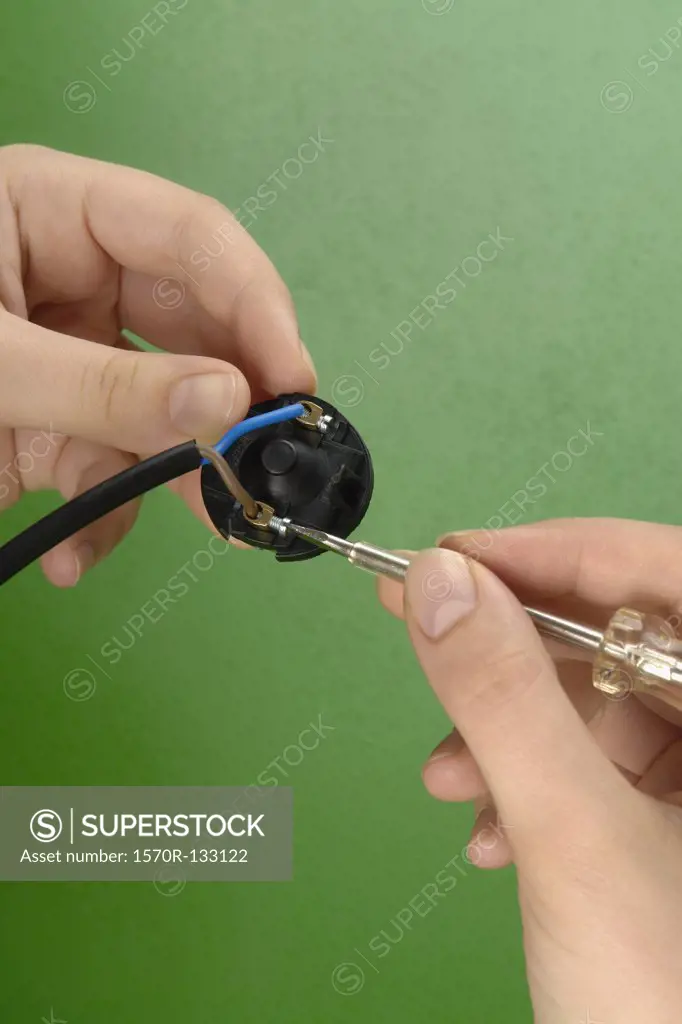 Detail of a woman holding a screwdriver and a cable