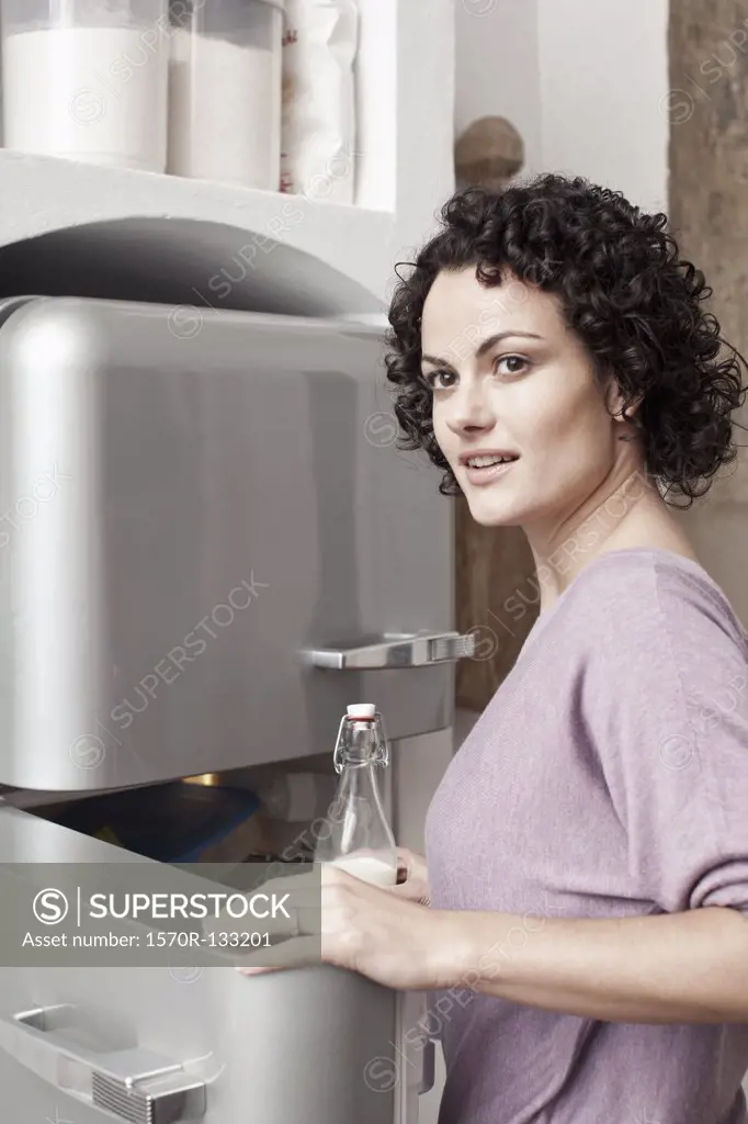A woman putting milk in the fridge