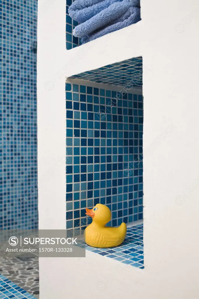 A rubber duck on a tiled bathroom shelf