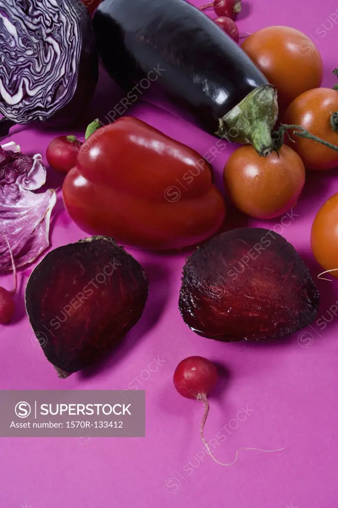 Arrangement of red and purple vegetables on a pink background