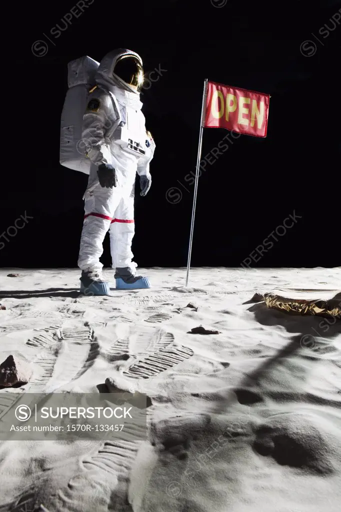 An astronaut on the moon next to a flag with OPEN on it