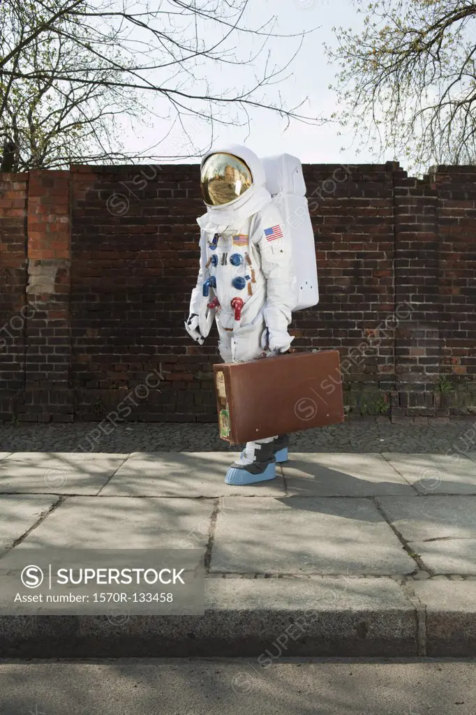 An astronaut carrying a suitcase and walking on a city sidewalk