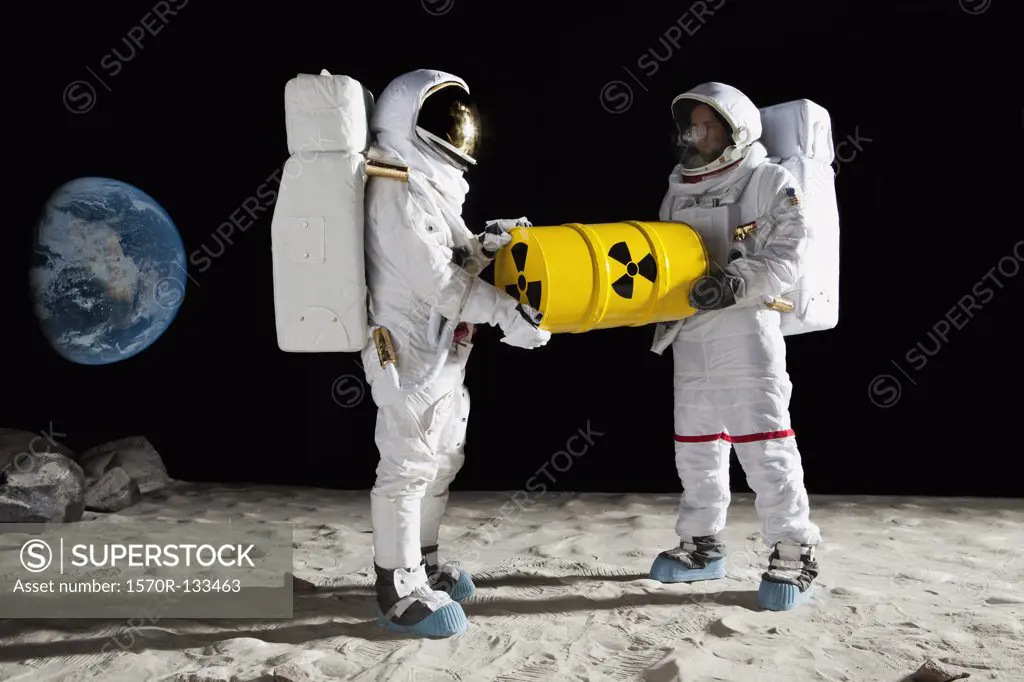 Two astronauts on the moon surface carrying a drum of toxic material