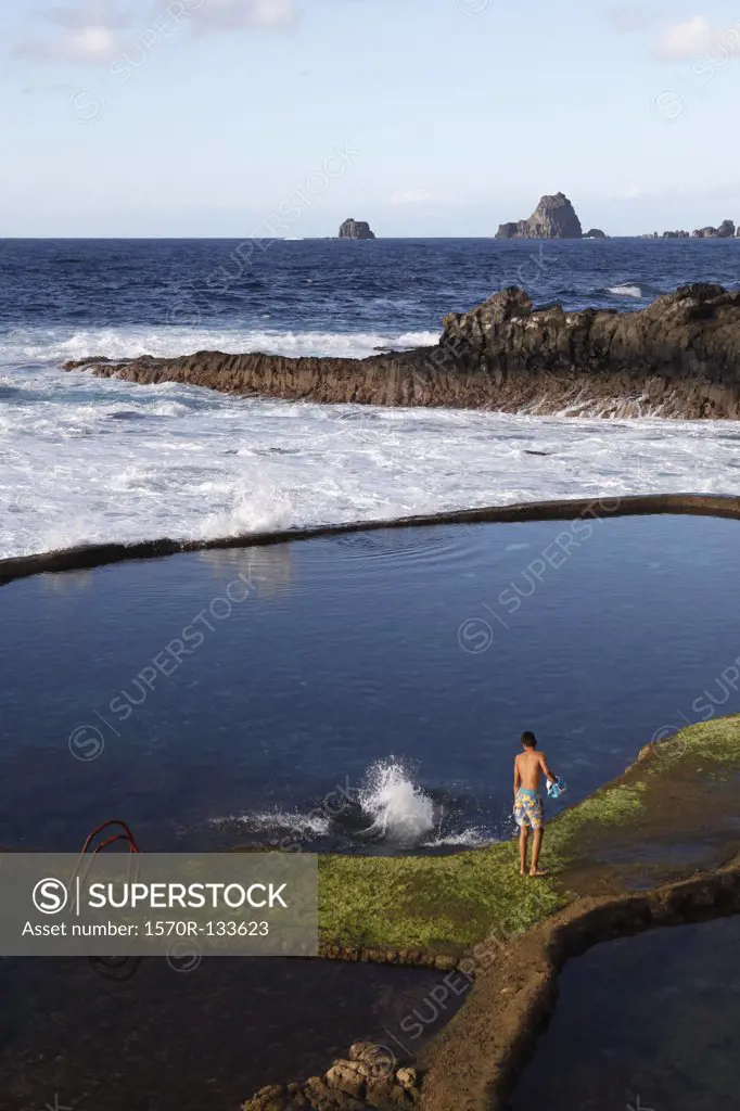 View of a boy standing by rock pools